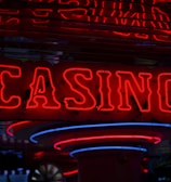 Neon lights display the word 'CASINO' in bright red, standing out against a dark background. The vibrant glow reflects a lively and bustling atmosphere.