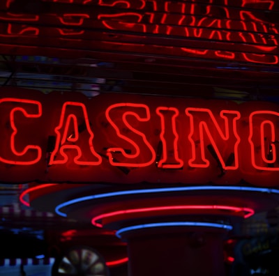 Neon lights display the word 'CASINO' in bright red, standing out against a dark background. The vibrant glow reflects a lively and bustling atmosphere.