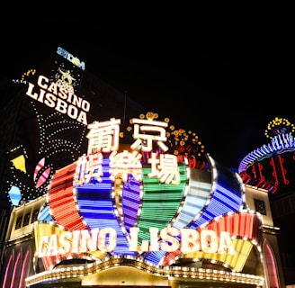 Bright neon signs in multiple colors illuminate the night, prominently displaying the name 'Casino Lisboa' alongside signage in Chinese characters. The lights form intricate patterns and vibrant displays, creating a lively and energetic atmosphere.